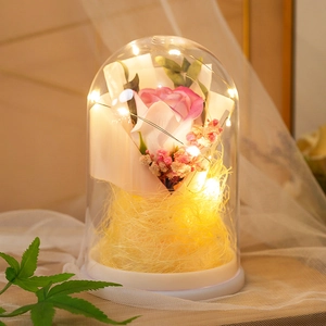 Pink preserved rose in glass dome with LED warm lights on a white base for home decor