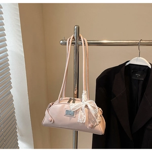 Detail of light pink leather shoulder bag featuring a lace bow and silver brand plate
