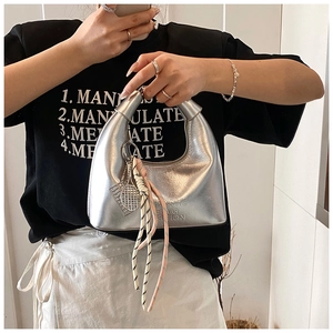Détail du sac hobo argenté avec pendentif raquette de tennis et pompon tissé chic