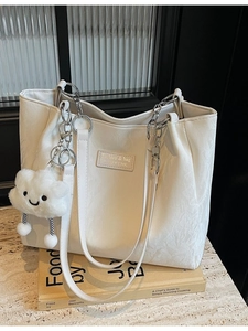 Minimalist white tote bag with wrinkled leather texture and cloud plush keychain