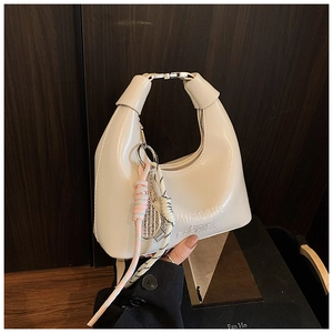 Détail du sac à main blanc brillant en forme de lune avec pendentif et logo embossé