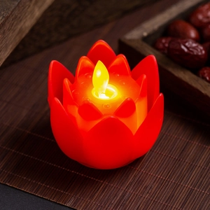 Close-up of a red LED lotus candle with a warm flickering flame on a bamboo mat