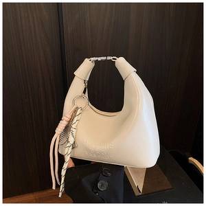 Vue détaillée du sac à main blanc avec lettres embossées et charm de ruban rose