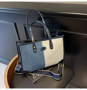 Detail of denim and canvas patchwork tote bag with navy leather handles and gold hardware