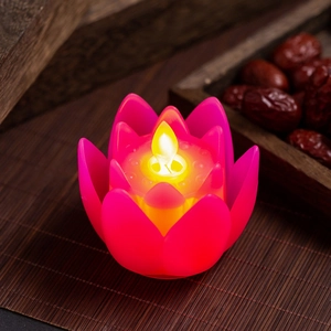 Detail of pink lotus LED candle with warm yellow light on a traditional bamboo mat
