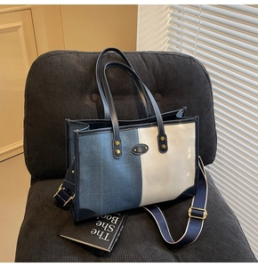 Detail of a two-tone denim tote bag with gold metal hardware on a corduroy seat