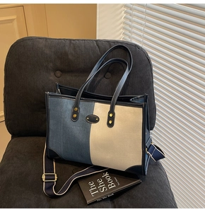 Detail view of large blue and white tote bag with detachable wide strap and golden buckle