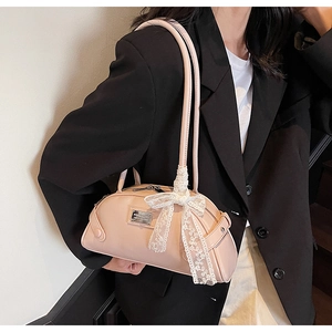 Detail of pink dumpling shoulder bag with white lace bow and silver brand plaque