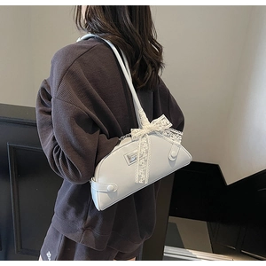 Detail of light blue shoulder bag with lace bow decoration and metallic silver logo plate