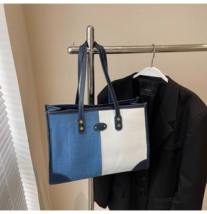 Close-up of contrast stitching on blue denim and white canvas tote bag with metal rivets