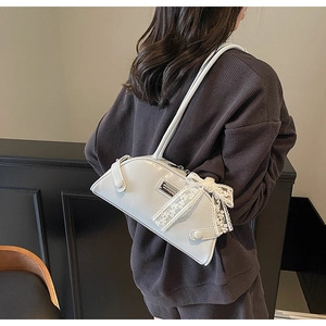 Close-up of white bowling-style shoulder bag with elegant lace bow detail