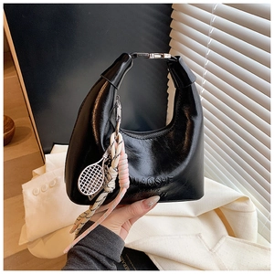 Détail du sac hobo noir brillant avec logo embossé et breloque raquette de tennis