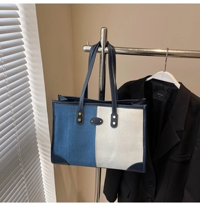 Detail of denim and canvas patchwork tote bag with gold studs and leather handles