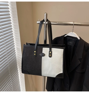 Detail of contrast canvas tote bag with leather handles and gold rivet accents