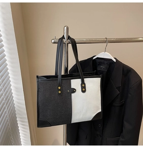 Detail of contrast stitch tote bag with gold rivets and black leather trim accents