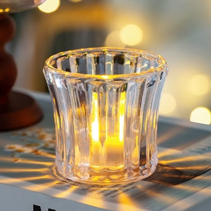 Close-up of a fluted glass crystal candle holder with a warm glowing light on books