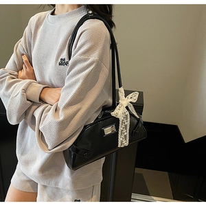Glossy black patent leather underarm bag featuring a white lace bow charm and silver logo
