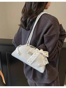 Light blue patent leather bowling bag with lace bow accessory shown on model's shoulder