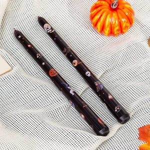 Set of two black Halloween taper candles with pumpkin and ghost prints for holiday decor