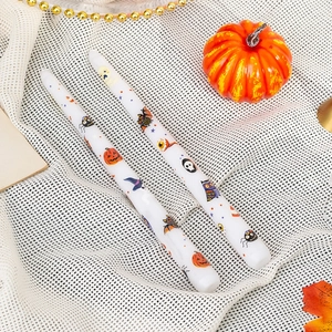 Detail of Halloween paraffin candles with pumpkin and bat prints on white mesh fabric