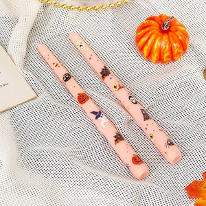 Detail view of 25cm pink Halloween taper candles with pumpkin and ghost illustrations