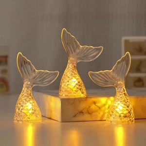 Three mermaid tail LED night lights with scale texture on marble surface