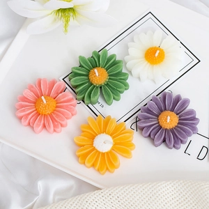 Detailed top view of daisy-shaped scented candles in various pastel colors on a silk fabric