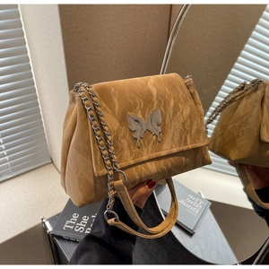 Detail of tan crinkled leather shoulder bag with a silver butterfly metal clasp ornament
