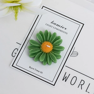 Top-down macro shot of dark green daisy candle with yellow core and white cotton wick