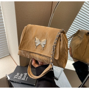 Close-up of brown pleated shoulder bag featuring a silver butterfly buckle and chain strap