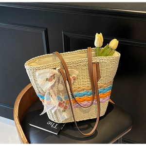 Detail of straw tote bag with colorful woven stripes and floral lace bow decoration