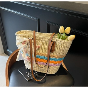 Detail of bohemian straw tote bag with colorful woven stripes and floral lace bow