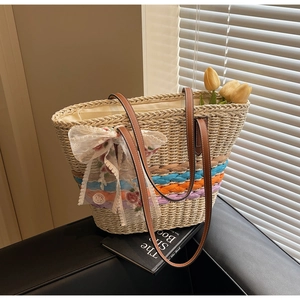 Close-up of woven straw tote bag with colorful stripes and lace flower ribbon detail