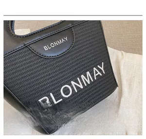Detalle del bolso de hombro negro BLONMAY que muestra el logo metálico y las costuras