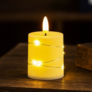 Detail of warm white LED flameless candle wrapped in copper wire fairy lights on wood