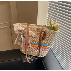 Detail of straw tote bag with color-woven stripes and floral lace bow decoration