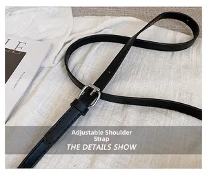 Detalle de correa ajustable de cuero negro con hebilla plateada en un bolso de mano elegante