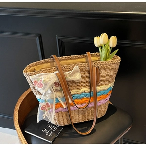 Detail of handmade straw tote with colorful weaving, lace, and brown leather straps