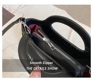 Detalle de cremallera metálica suave y forro burdeos en un bolso de cuero negro