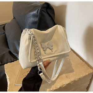 Detail of creamy white tote bag featuring a fluid silver metal butterfly and chain strap