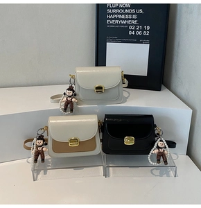 Close-up of minimalist crossbody bags with gold buckles and cute pearl doll charms