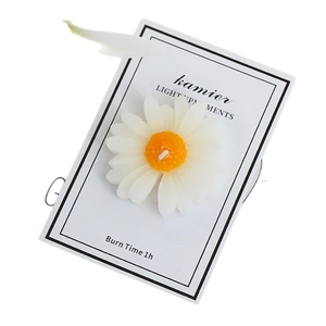 Daisy shaped scented candle with white petals and yellow core on a display card