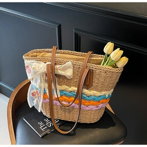 Detail of colorful woven stripes and white lace flower bow on a straw tote bag