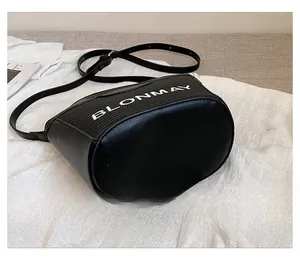 Detalle de la base ovalada de un bolso bucket negro de cuero con letras del logo de marca