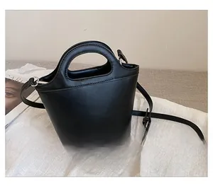 Vista trasera de un bolso cubo minimalista de cuero negro con asa superior rígida