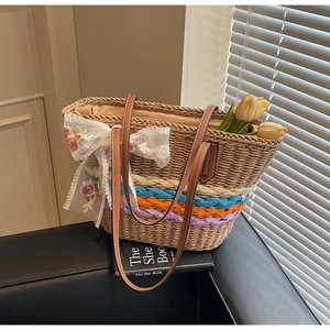 Detail of straw tote bag with rainbow woven straps, lace floral bow, and leather handles