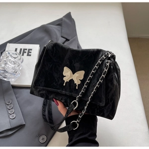 Detail of black pleated tote bag featuring a metallic cream butterfly clasp and silver chain