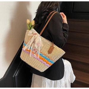 Close-up of handmade straw tote bag with multi-color stripes and floral lace ribbon detail