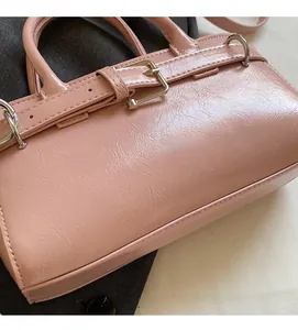 Detalle de bolso tipo cubo rosa con textura plisada y adornos de hebilla plateada