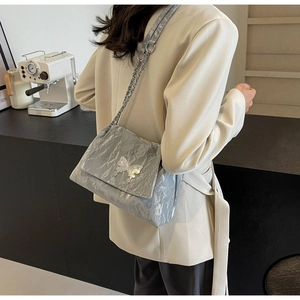 Detail of silver tote bag with shiny crinkle texture and metallic butterfly buckle
